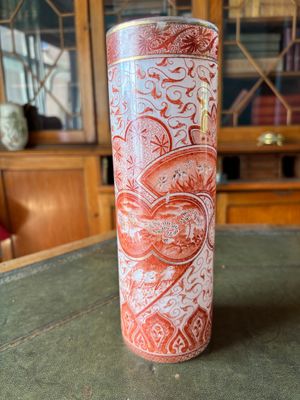 a red and white vase sitting on top of a table