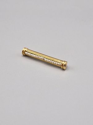 un gros plan d'une broche dorée sur une surface blanche