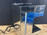 a silver box with a blue object in it on a wooden table