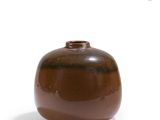 a brown vase that is sitting on a white surface