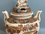a small teapot with a buddha on it