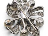 an image of a silver brooch with pearls on a white background