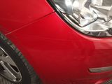 a close up of a red car ' s headlight and front bumper