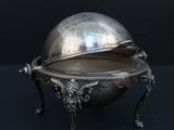 un plat ancien en argent avec un couvercle bombé, posé sur un socle
