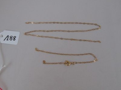 two gold chains and a bracelet are on a white table