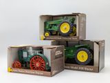 three toy tractors in a box on a white surface