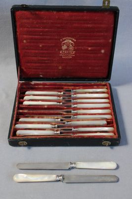un étui contenant un ensemble de couteaux et sur lequel est posé un couteau