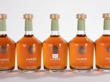 quatre bouteilles d'alcool sont alignées les unes à côté des autres sur une surface blanche