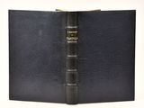 un vieux livre à la couverture noire posé sur une table blanche