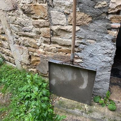 un vieux téléviseur posé par terre à côté d'un mur de pierre