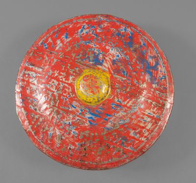bol peint en rouge et bleu, avec un centre jaune sur un fond gris
