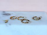 three pairs of gold hoop earrings sitting on a marble slab
