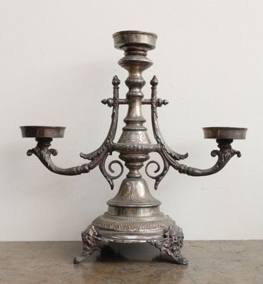 un bougeoir en argent posé sur une table, avec deux bougies