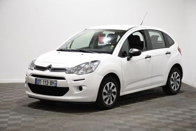 La petite voiture blanche est garée dans une pièce au sol carrelé en damier.