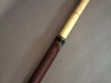 an old pen with a wooden handle sitting on top of a white surface