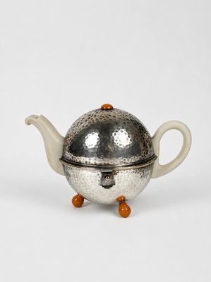 une vieille théière en argent avec son couvercle, sur fond blanc