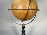 un gros plan d'un globe terrestre en bois posé sur un socle, sur fond blanc