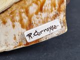 a close up of a piece of pottery with a name tag on it