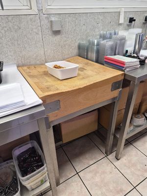 une cuisine équipée d'un évier et d'un plan de travail sur lequel se trouve une planche à découper
