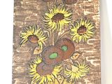 un tableau représentant des tournesols dans un vase, accroché au mur