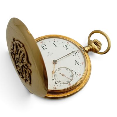 une montre de poche en or posée sur une surface blanche