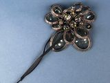 a black and gold flower brooch on a blue surface