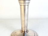 un bougeoir en argent posé sur une table blanche