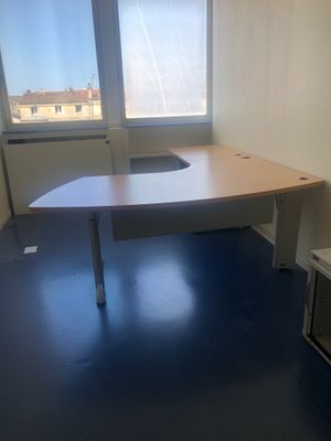un bureau dans un coin d'une pièce, avec une fenêtre en arrière-plan