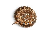 a gold brooch on a white surface with a white background
