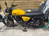 a yellow and black motorcycle parked next to a wooden wall