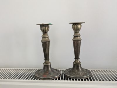 deux bougeoirs en argent posés sur une étagère