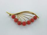 gold plated brooch with red beads on a white background