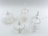 three clear glass teapots and a saucer on a white surface
