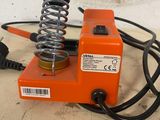 a close up of a small orange machine with a spring on top of it