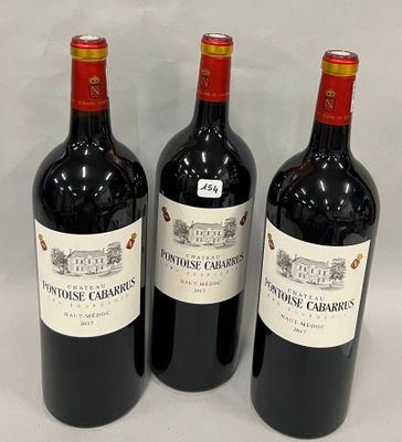 trois bouteilles de vin rouge sont alignées sur une surface blanche