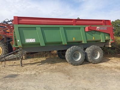 un camion-benne vert et rouge garé à côté d'un tracteur rouge