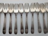 six forks and six spoons on a white table