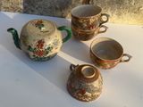 trois tasses et une théière posées sur une table