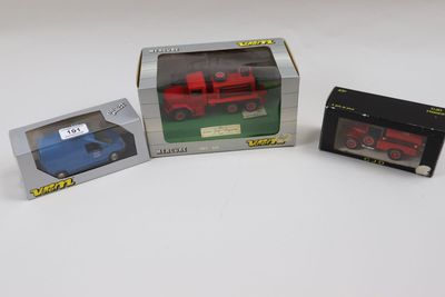 trois camions miniatures dans une boîte posée sur une surface blanche