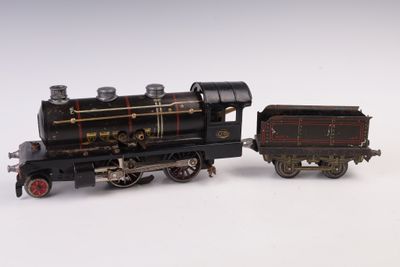 un petit train miniature posé sur une surface blanche, à côté d'un autre plus petit