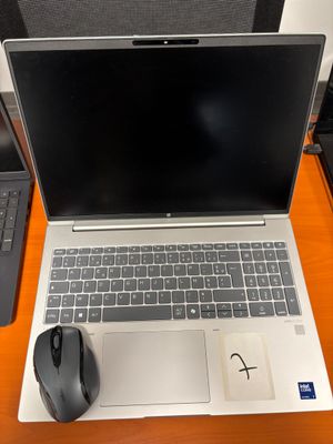 un ordinateur portable posé sur un bureau, à côté d'une souris