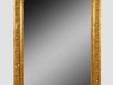 une image représentant un miroir à cadre doré posé sur un mur blanc
