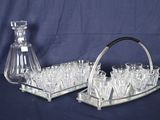 des bouteilles et des verres disposés sur un plateau en argent, avec une carafe en verre sur fond bleu