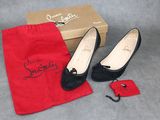 une paire de chaussures noires pour femme dans un sac rouge, à côté d'une paire de chaussures rouges
