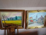 two paintings hanging on a wall in a room with a chair