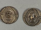 two silver buttons with a lion head on them sitting on a table