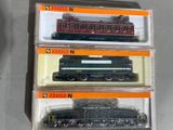 trois trains miniatures dans leurs boîtes, empilés les uns sur les autres sur une table