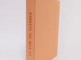 an orange book sitting on top of a white table next to a white wall