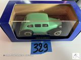 une petite voiture verte dans une boîte bleue posée sur une table