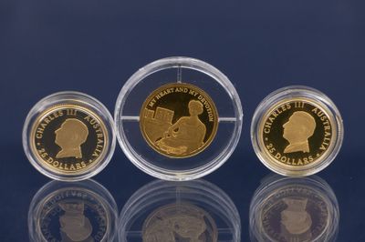 trois souverains d'or dans des étuis en acrylique posés sur un fond bleu